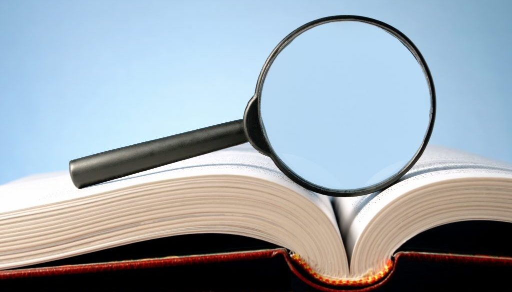 12247812 - magnifying glass and an open book on a table